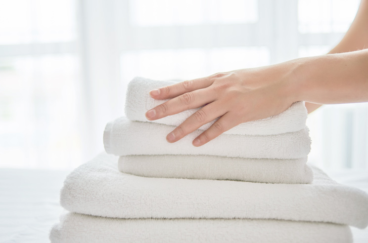 Plan rapproché d'une personne déposant des serviettes de bain pliées